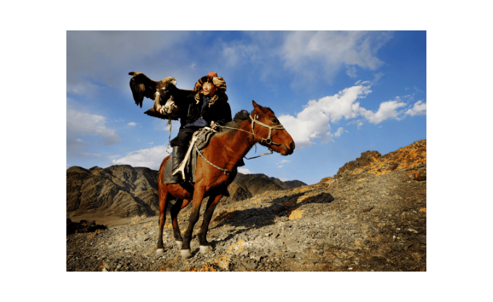 Kazakh eagle hunter on horseback during hunting with eagles in Mongolia cultural tour