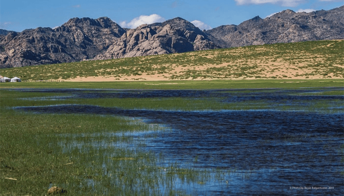 Khentii Mountains sanctuary in Mongolia with pristine wetlands, grasslands, and rugged peaks under clear blue sky