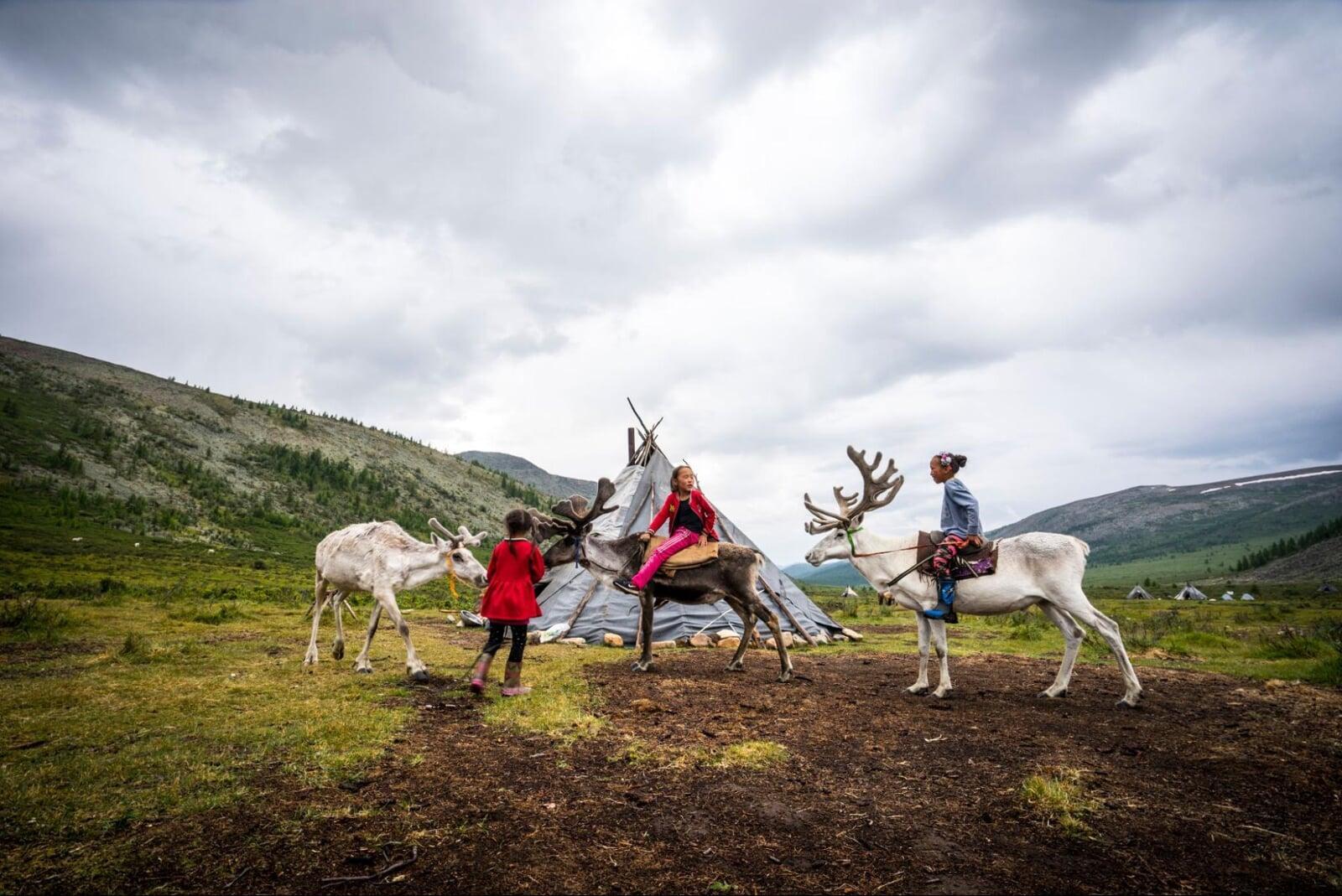 Northern Mongolia reindeer herders near Khuvsgul Lake with traditional teepee camp and dramatic mountain landscape.