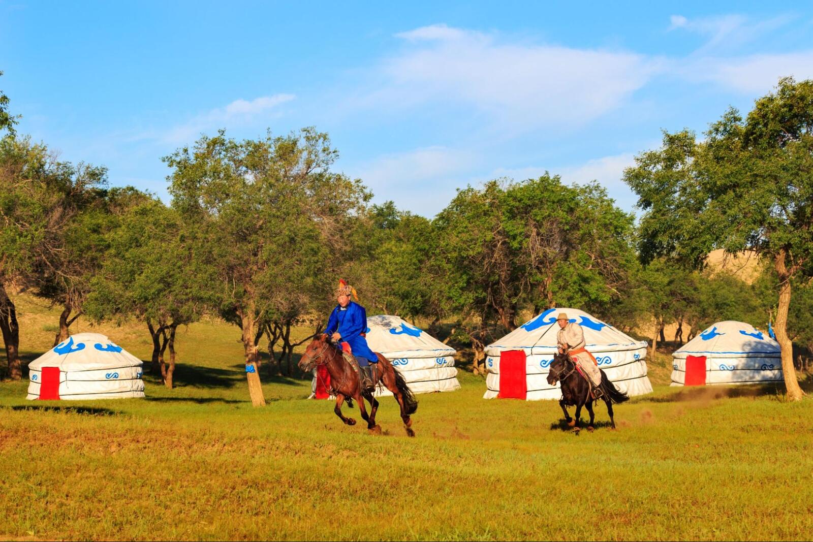 Horseback riding in Mongolia for beginners with traditional yurts and riders in scenic grassland landscape