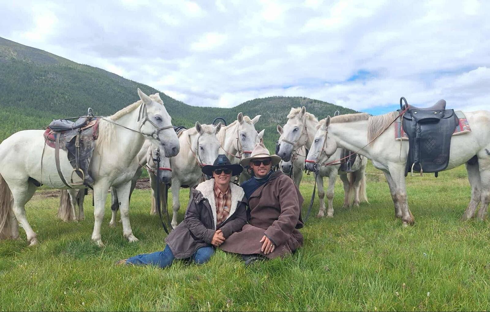 Group with horses on Mongolia horse tour in green valley landscape